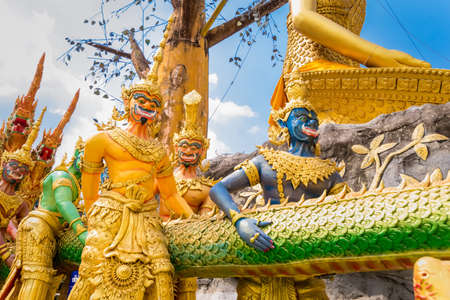 Nakhon Nayok, Thailand - March, 28, 2021 : Golden statue of angel and demons doing tug of war with three-headed serpent, depicting good and evil contest at Maniwong Temple at Nakhon Nayok, Thailand.のeditorial素材