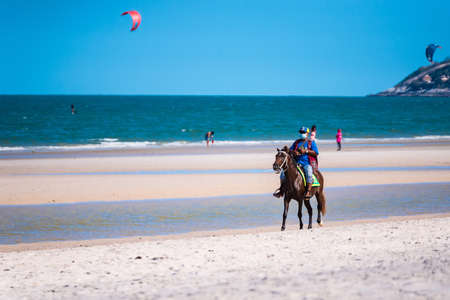 Prachuap Khiri Khan, Thailand- April, 03, 2021 : Unidentified name People horseback riding at Hua hin beach on hot sun during the day in Hua Hin, Thailand.Looking for customers to rent horses to ride on the beach.のeditorial素材
