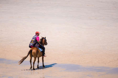 Prachuap Khiri Khan, Thailand- April, 03, 2021 : Unidentified name People horseback riding at Hua hin beach on hot sun during the day in Hua Hin, Thailand.Looking for customers to rent horses to ride on the beach.のeditorial素材