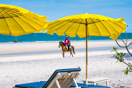 Prachuap Khiri Khan, Thailand- April, 03, 2021 : People horseback riding at Hua hin beach on hot sun during the day in Hua Hin, Thailand.Looking for customers to rent horses to ride on the beach.のeditorial素材