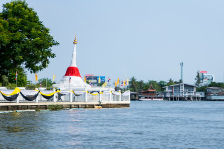 Nonthaburi, Thailand- March, 27, 2021 : white leaning pagoda has a red cloth tied at the top beside Chao Phraya river at Koh kret at Nonthaburi, Thailandのeditorial素材