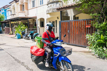 Bangkok, Thailand-June, 05, 2021: A delivery man rides a motorcycle to deliver goods in the village at Bangkok, Thailandのeditorial素材