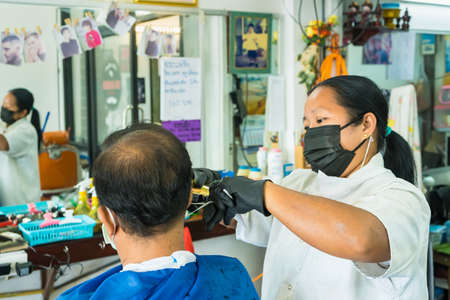 Bangkok, Thailand-June, 11, 2021: Hairdresser and customer in a salon with medical masks during virus pandemic. Working with safety mask at Bangkok, Thailandのeditorial素材