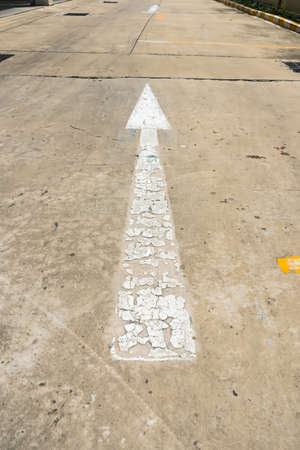 White street arrow sign on cement floor at day time