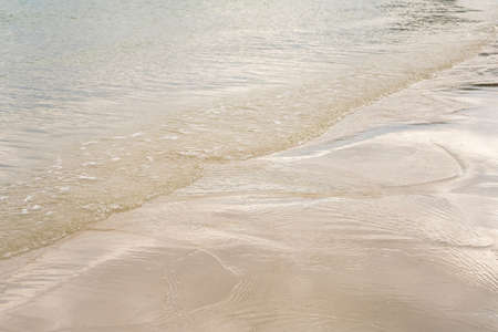transparent water ripple and sunlight glare on white sand backgroundの写真素材
