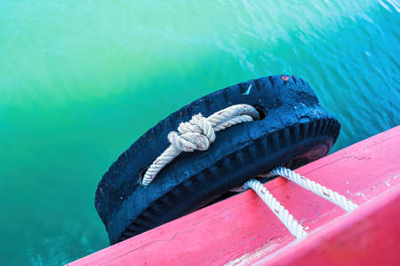 Close-up at tire wheel on ship body which is used as safety bumper, during the ship is moving on the sea. Travel transportationの写真素材