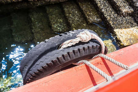 Close-up at tire wheel on ship body which is used as safety bumper, during the ship is moving on the sea. Travel transportationの写真素材