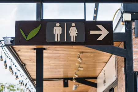 Black wooden square shape of public restroom toilet sign for man and woman closeup roof indoor blur backgroundの写真素材