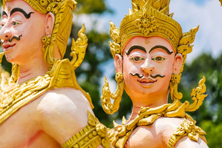 Nakhon Nayok, Thailand - April, 24, 2022 : Golden statue of angel and demons doing tug of war with three-headed serpent, depicting good and evil contest at Maniwong Temple at Nakhon Nayok, Thailand.のeditorial素材