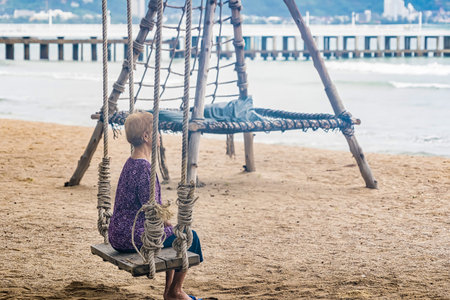 Phuket, Thailand - May, 07, 2022 :Unidentified name tourist Asian old woman sitting on a swing at a paradise beach in the Phuket coast.Thailand.のeditorial素材