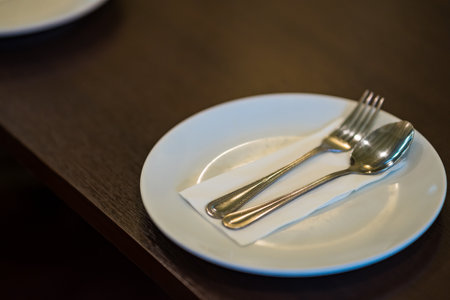 silver spoon and fork with white dish on wooden background.の写真素材