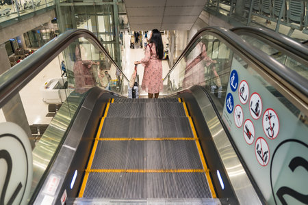 Bangkok,Thailand - September,23, 2022: Unidentified name women with a carry-on baggage riding escalator in airport terminal at Bangkok,Thailand.のeditorial素材