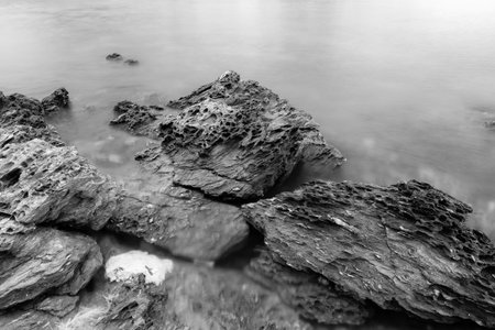 Black and white photo of long exposure of the sea with rocks.の写真素材