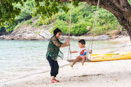 Rayong, Thailand - October, 15, 2022 : Asian grandmother have fun with her little boy to play together with swing at the Koh Samet island, Rayong, Thailandのeditorial素材