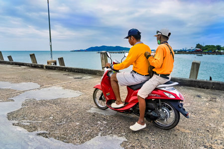 Rayong, Thailand - October, 15, 2022 : Man ride old motorcycle on the chaolao harbor bridge in the morning over cloudy sky at Rayong, Thailandのeditorial素材