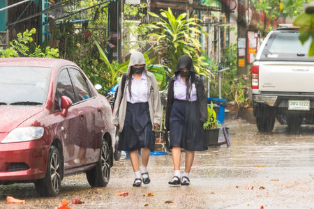 Bangkok, Thailand - February, 14, 2023 : Two Asian female students walking home in the rain at Bangkok, Thailandのeditorial素材