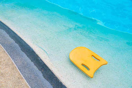 Yellow kick board made of foam floating on water surface in swimming pool.の写真素材