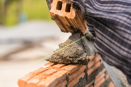 Hand worker masonry brickwork trowel construction site wall concrete backgroundの写真素材