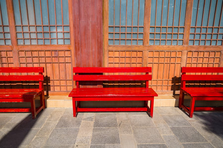 Red wood bench in front old wooden houseの写真素材