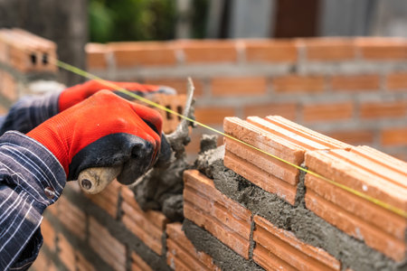 Hand worker masonry brickwork trowel construction site wall concrete backgroundの写真素材