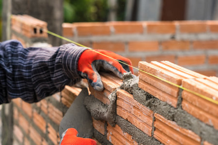 Hand worker masonry brickwork trowel construction site wall concrete backgroundの写真素材