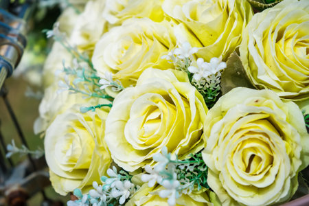 A close-up of a bicycle basket filled with fresh yellow roses, creating a charming and romantic outdoor scene.の写真素材