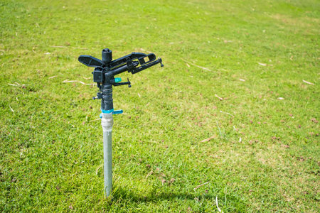 Efficient lawn sprinkler system watering a vibrant green lawn, ensuring healthy grass growth.の写真素材