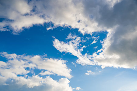 The sunlight illuminates the clouds, giving them a soft, radiant appearance. The blue sky in the background is clear, with a gradient of lighter hues towards the horizon.の写真素材
