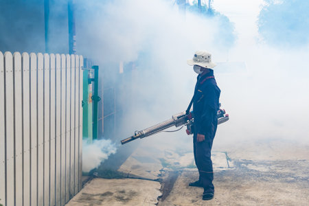 A health worker uses a fogging machine to control mosquito populations in an urban setting.のeditorial素材