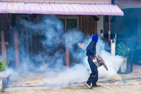 A health worker uses a fogging machine to control mosquito populations in an urban setting.のeditorial素材