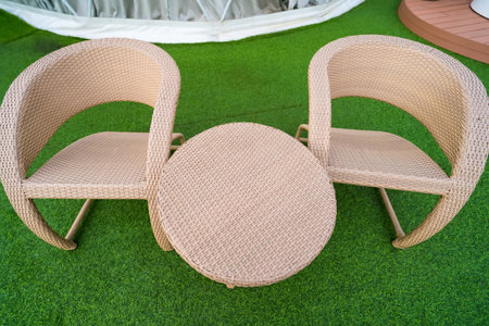 An outdoor wicker sofa and table set with a circular design, placed on green artificial grass with a bamboo backdrop, ideal for creating a cozy outdoor seating area.の写真素材