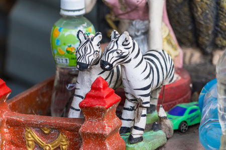 Traditional handcrafted zebra figurines arranged with red decorations and plastic bottlesの写真素材
