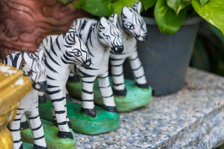 Traditional handcrafted zebra figurines arranged with red decorations and plastic bottlesの写真素材