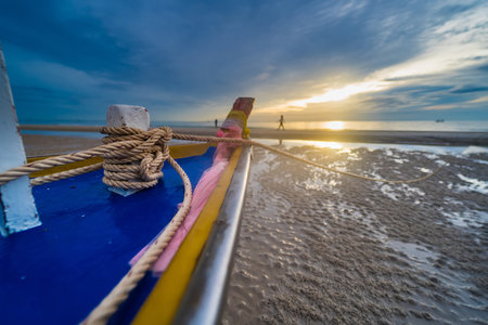 A fishing boat at dawn, with the sky painted in hues of blue and orange, reflecting the beauty of the early morning.の写真素材