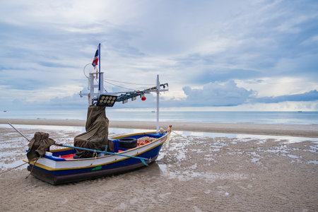 A fishing boat at dawn, with the sky painted in hues of blue and orange, reflecting the beauty of the early morning.の写真素材