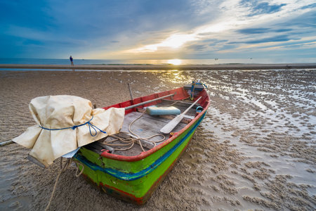 A fishing boat at dawn, with the sky painted in hues of blue and orange, reflecting the beauty of the early morning.の写真素材