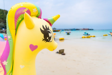 A stack of colorful animal-shaped inflatable floats, including flamingos and unicorns, is ready for fun water activities on the beach.の写真素材