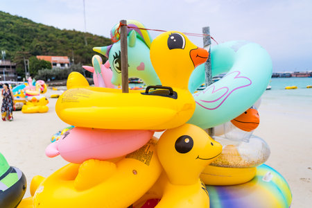 A stack of colorful animal-shaped inflatable floats, including flamingos and unicorns, is ready for fun water activities on the beach.の写真素材