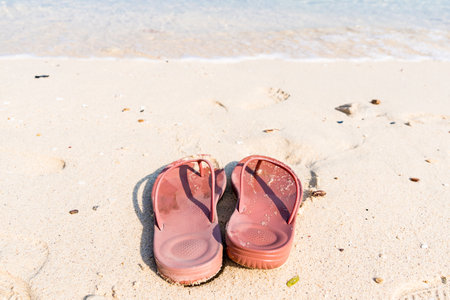 A tranquil beach scene featuring red flip-flops, symbolizing peaceful moments by the sea.の写真素材