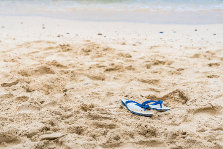 A tranquil beach scene featuring red flip-flops, symbolizing peaceful moments by the sea.の写真素材