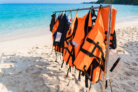 Essential marine safety gear, life jackets lined up on a sandy beach.の写真素材