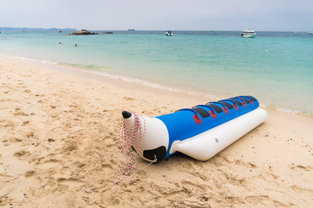 A peaceful beach scene with an inflatable banana boat waiting for adventurers; perfect for illustrating leisure and recreation.の写真素材