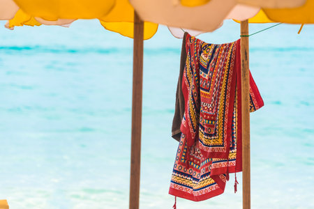 Description: A colorful towel under a yellow umbrella captures the essence of beach life.の写真素材