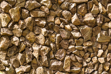 A close-up of a weathered stone wall with irregular shapes and earthy tones, perfect for creating a rustic or natural feel.の写真素材