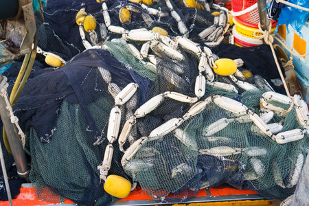 A close-up shot of tangled fishing nets with yellow and white buoys on a traditional Thai fishing boat.の写真素材