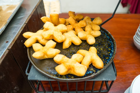 close-up of golden Patongo (Thai fried dough) arranged on a black tray. The crispy texture and warm color of the fried doughの写真素材