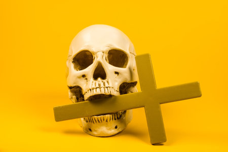 This striking image of a skull adorned with a cross against a vibrant yellow backdrop encapsulates the juxtaposition of mortality and spirituality, making it perfect for artistic projects.の写真素材