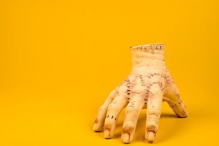 severed hand set against a bright yellow background is ideal for creating an unforgettable Halloween atmosphere.の写真素材