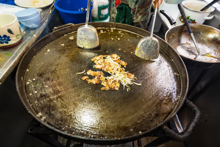 Street vendor cooking a traditional mussel pancake on a hot griddle.の写真素材