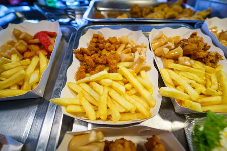 A variety of fried snacks and French fries served in paper trays at a food stall.の写真素材